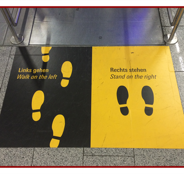 Bilingual floor decal marking a walking lane at a building entrance