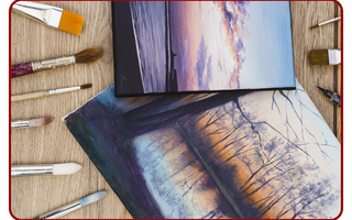 Canvas prints and artist brushes laid out on a wooden table