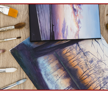 Canvas prints and artist brushes laid out on a wooden table