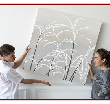 Two people hanging a large canvas print on an interior wall