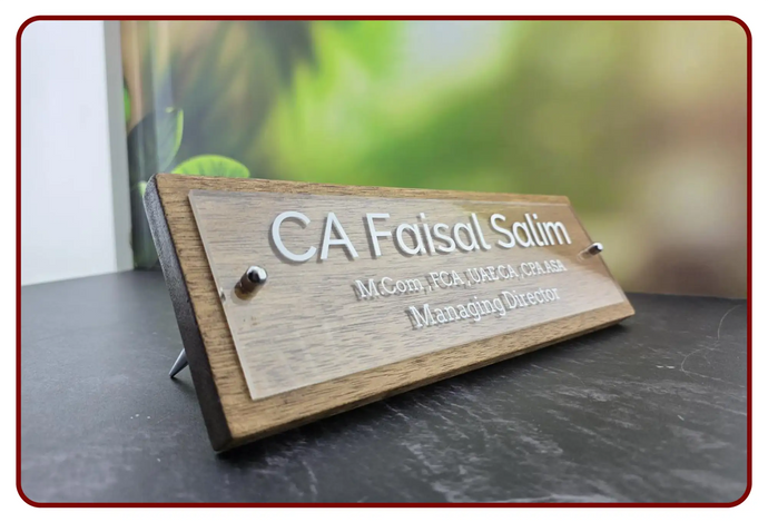 Wooden nameplate with silver engraved text displaying ’ca faisal salim’ and his professional titles.