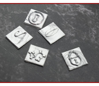 Close-up of engraved square brass wax stamp dies on a dark surface