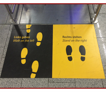 Bilingual floor decal marking a walking lane at a building entrance
