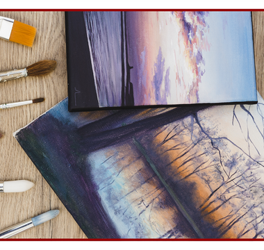 Canvas prints and artist brushes laid out on a wooden table