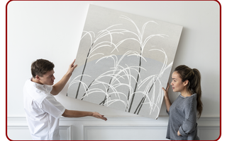 Two people hanging a large canvas print on an interior wall
