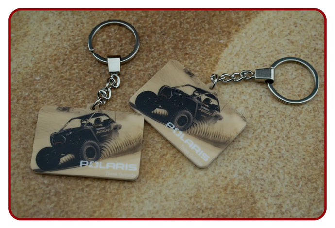 Monster truck keychain with black and white design on tan background, metal ring.